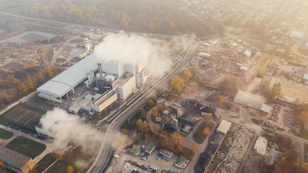 Een fabriek stoot grote witte rookpluimen uit