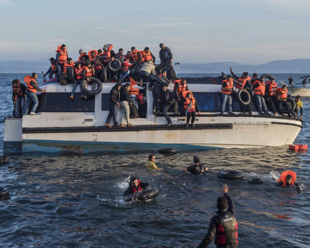 Vluchtelingen springen van een overvolle boot in Europese wateren